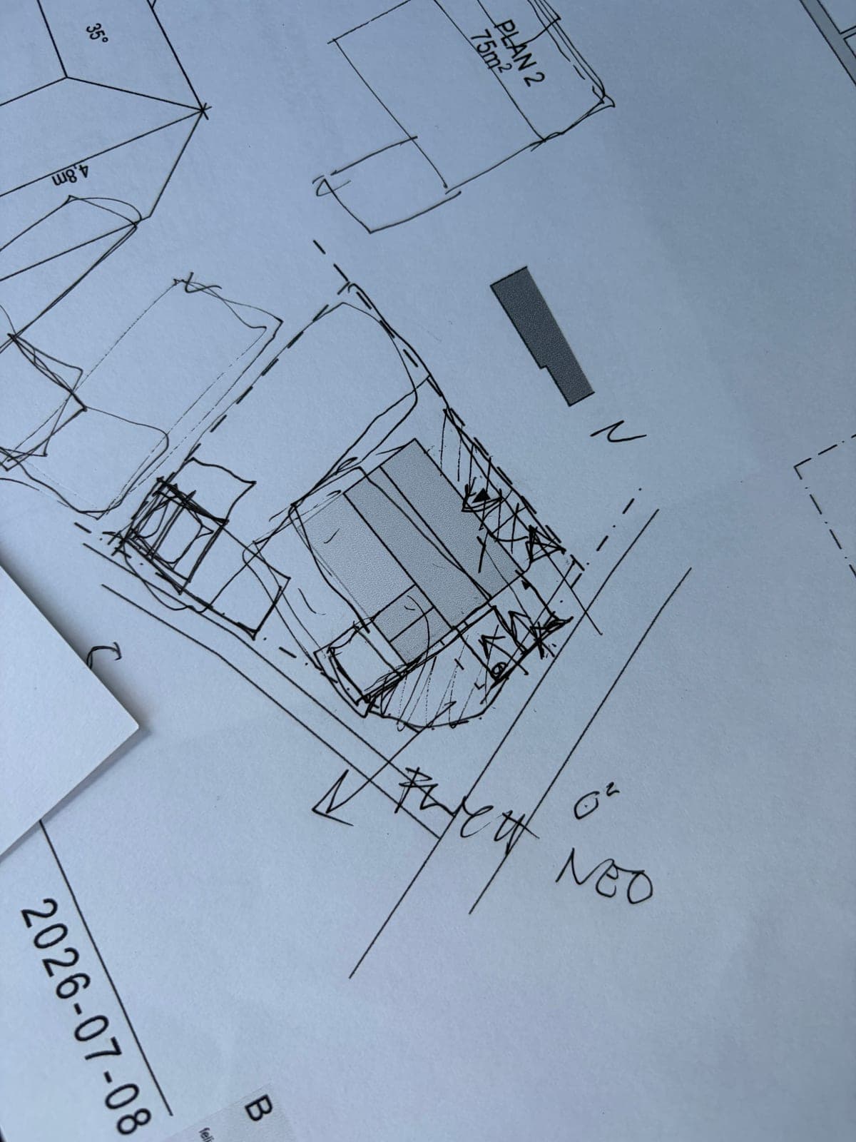 Handskiss av en situationsplan med byggnadsvolymer, ritad ovanpå utskrivna ritningar daterade 2026-07-08